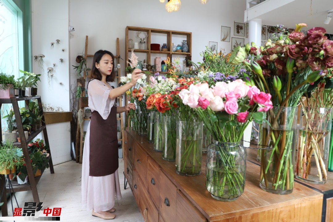 王黎媛是一名河南姑娘，在昆明念完大學(xué)后，就再也舍不下春城的藍(lán)天陽光、青山碧水，更舍不下這里的四時(shí)繁花，于是就干脆留了下來，成了一名媒體人。2017年的時(shí)候又毅然辭去工作，創(chuàng)業(yè)開起了花店，成了都市里的一名“花房姑娘”。圖為王黎媛在自己的花店中整理鮮花。新華網(wǎng) 周亞平/攝 念新洪/文